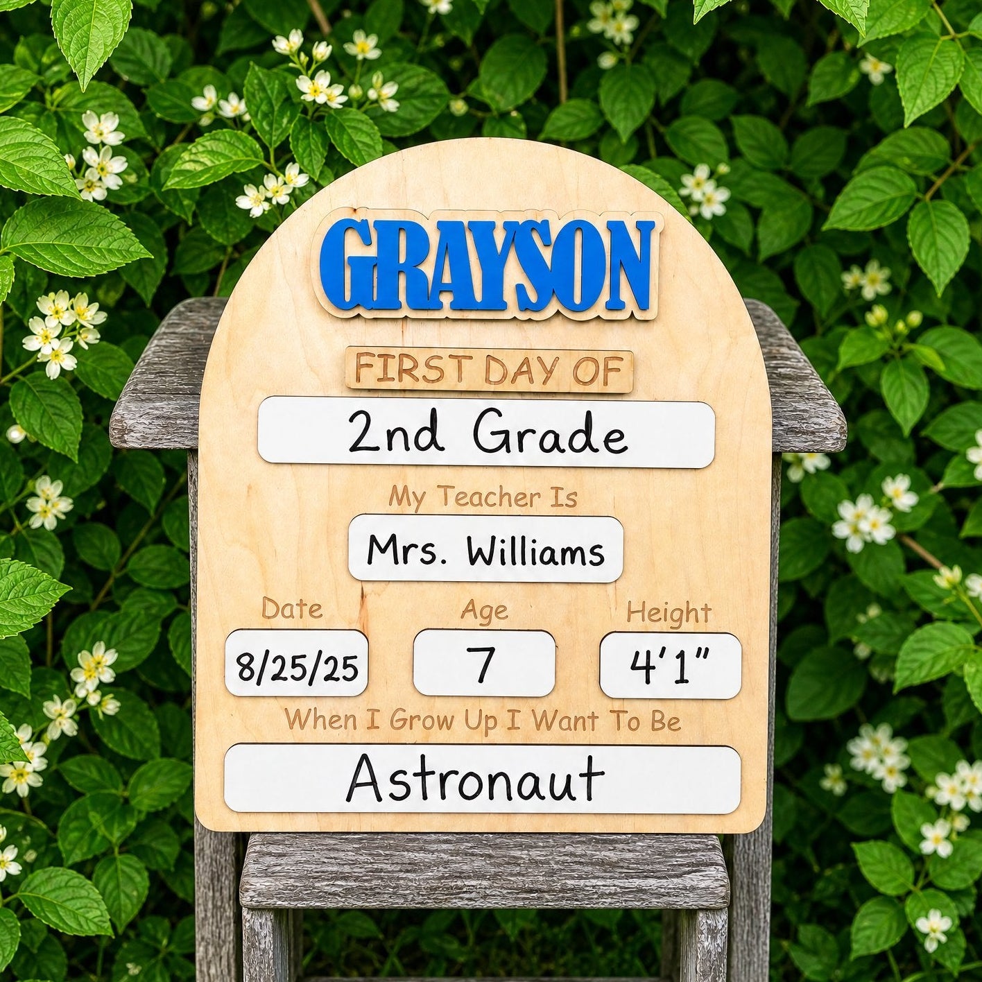 Personalized back to school milestone board with blue name GRAYSON, filled in for 2nd grade, displayed in garden setting