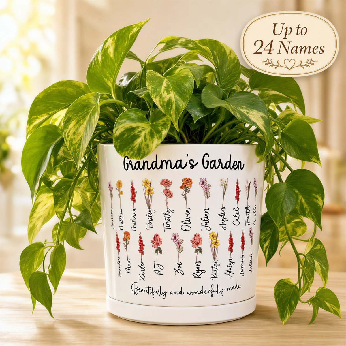 Personalized 'Grandma's Garden' Birth Flower Planter showing a white ceramic pot with watercolor floral designs and custom names. Features a lush green plant and a badge highlighting that the design accommodates up to 24 names, making it a perfect gift for Nana or Grandma.