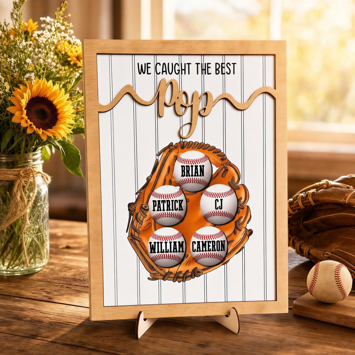 Personalized Father's Day baseball plaque for Pop. Features a rustic wood frame, 3D raised "Pop" lettering, and a printed baseball glove holding five custom grandkids' name baseballs, displayed on an easel.