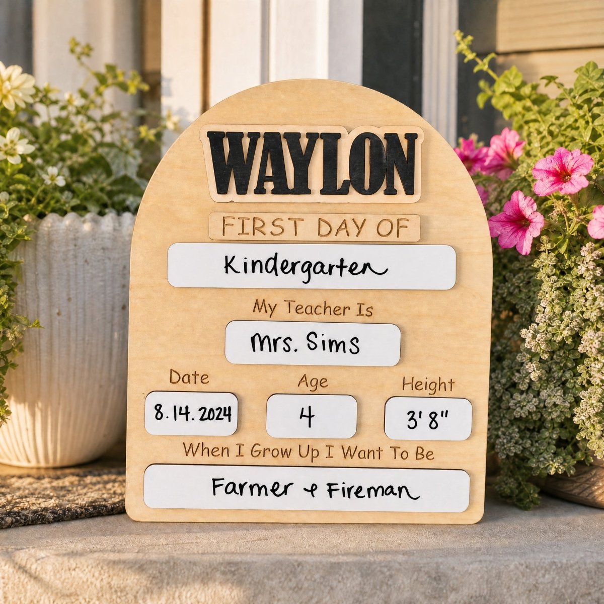 Personalized rounded arch first day of school sign Waylon standalone on front porch with potted flowers warm light