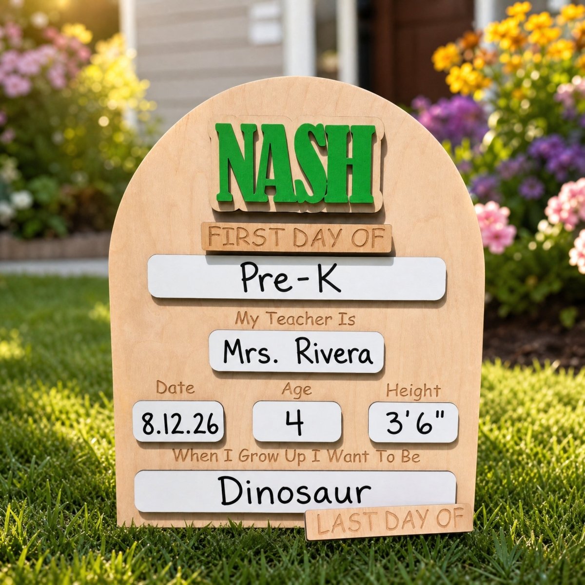 Personalized rounded arch first day of school sign Nash in green block font standalone lifestyle front yard flowers